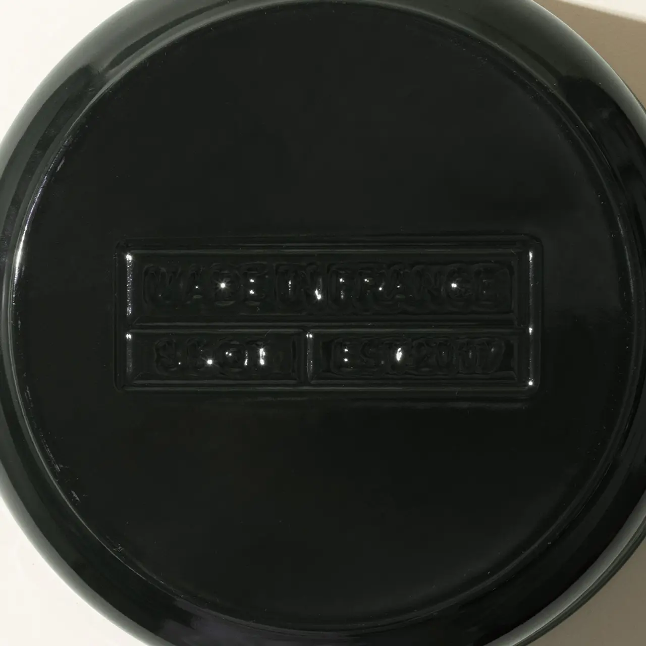 A black round object with an embossed design in the center that seems to be text or a logo, but is not clear due to the angle and lighting.