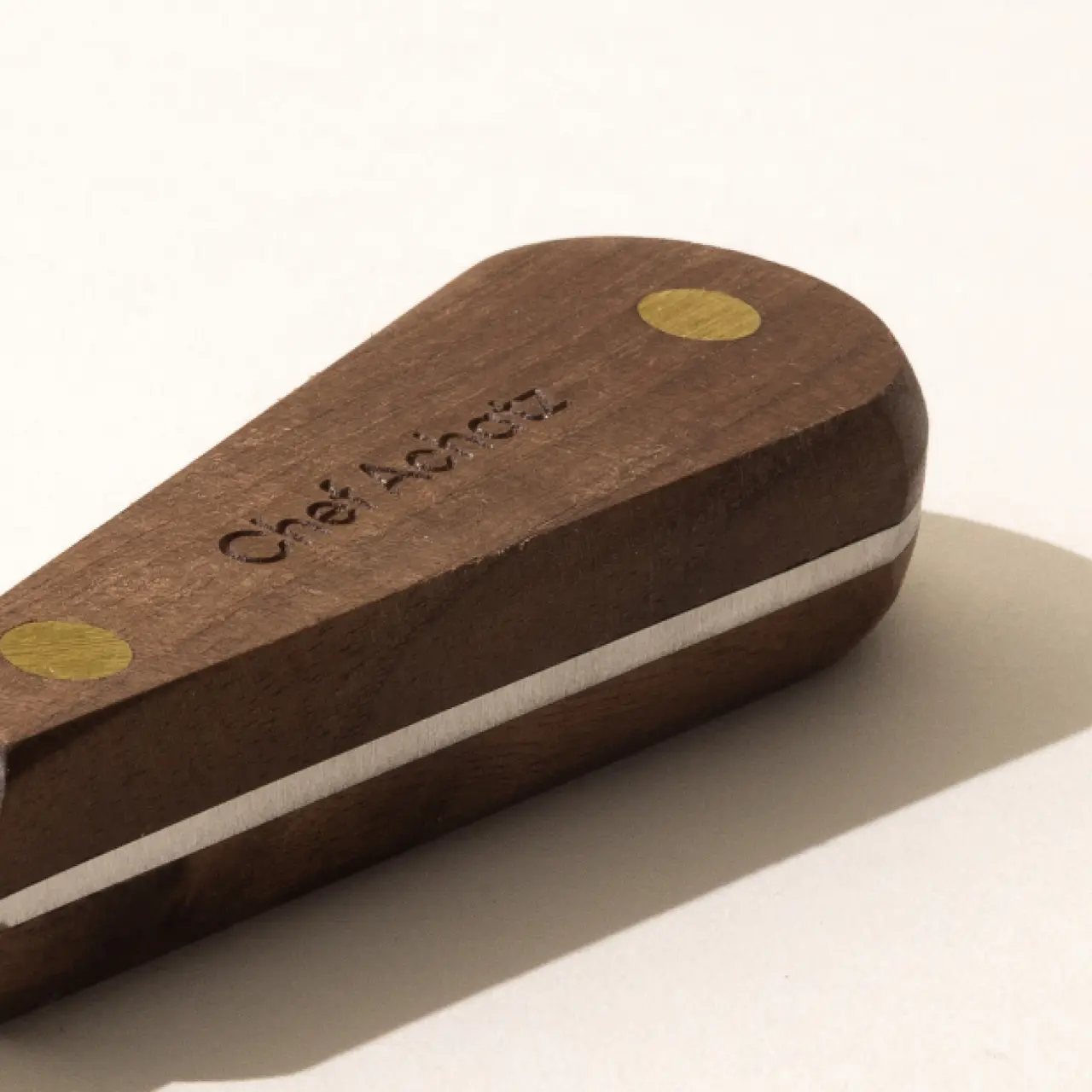 A wooden case with the embossed text "Chef's Pencil" on its surface, featuring light brown with darker brown edges and yellow circular accents.