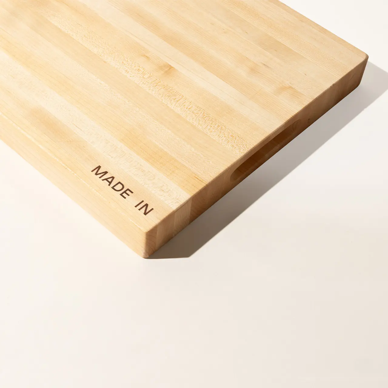 A close-up of a wooden board with "MADE IN" stamped on one corner, against a white background.