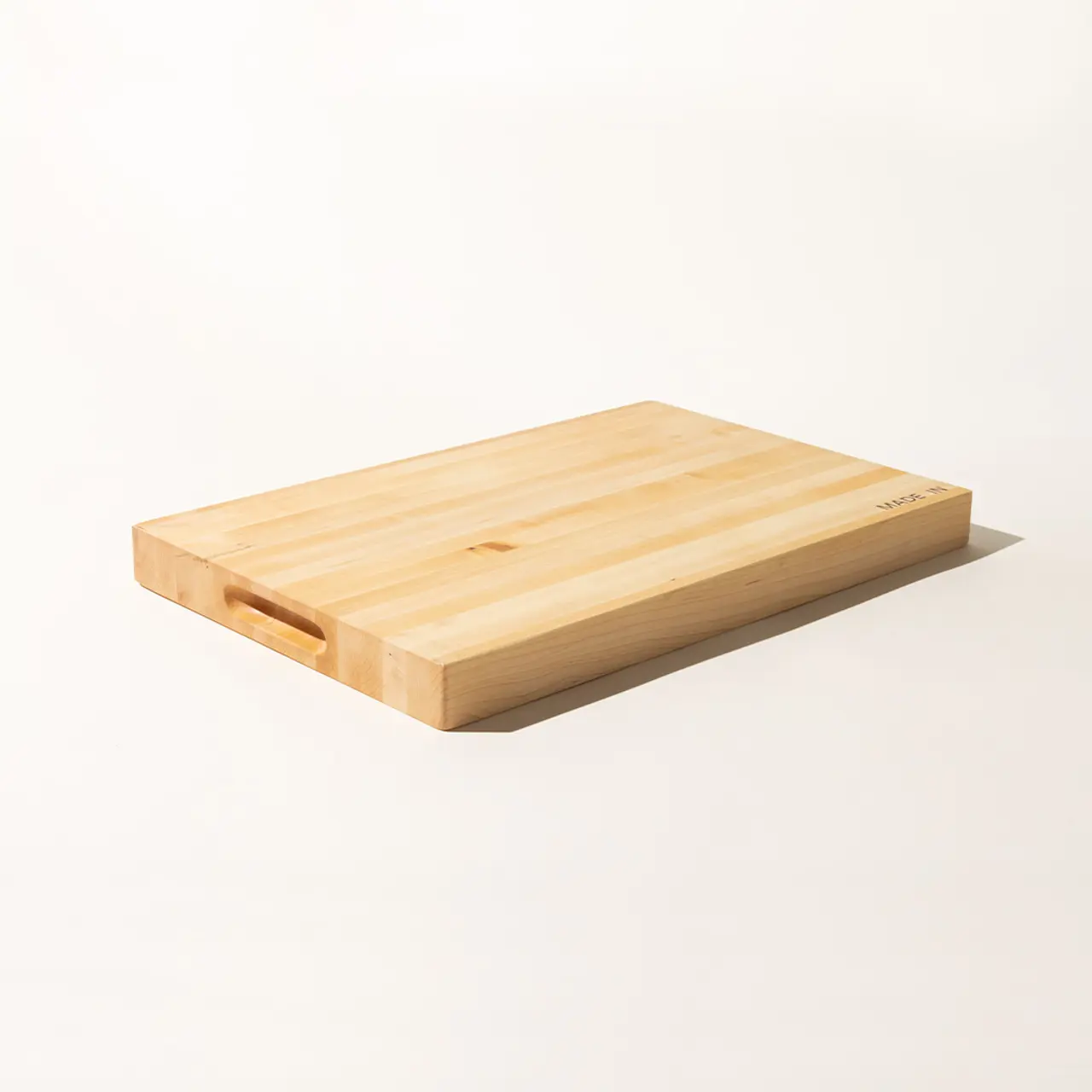 A wooden cutting board with a handle notch is isolated against a white background.