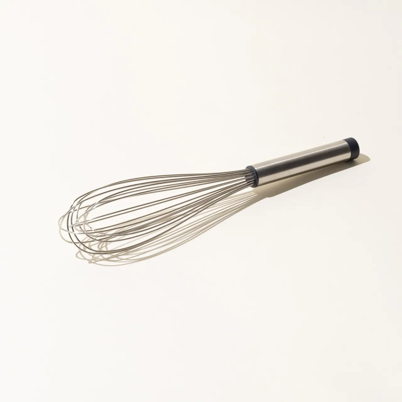 A stainless steel kitchen whisk with a black handle on a plain white background.