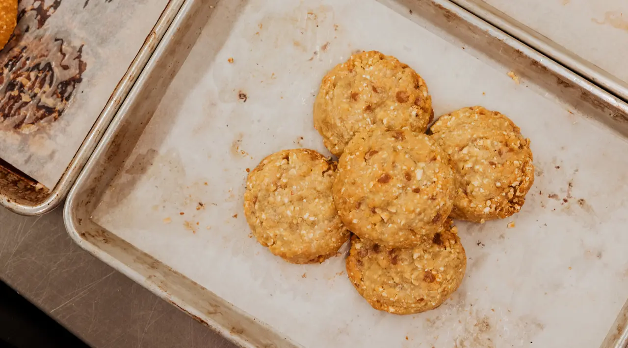 Baked cheese crisps are cooling on a parchment-lined baking tray.