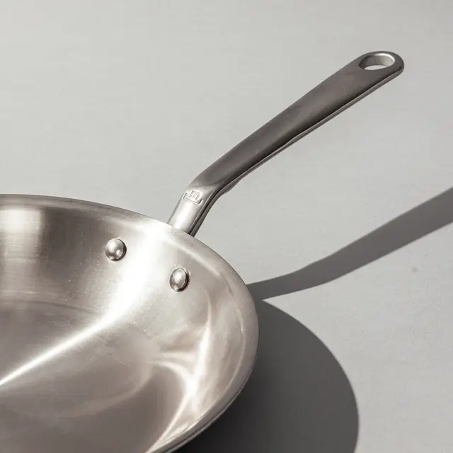 stainless steel frying pan on a grey background