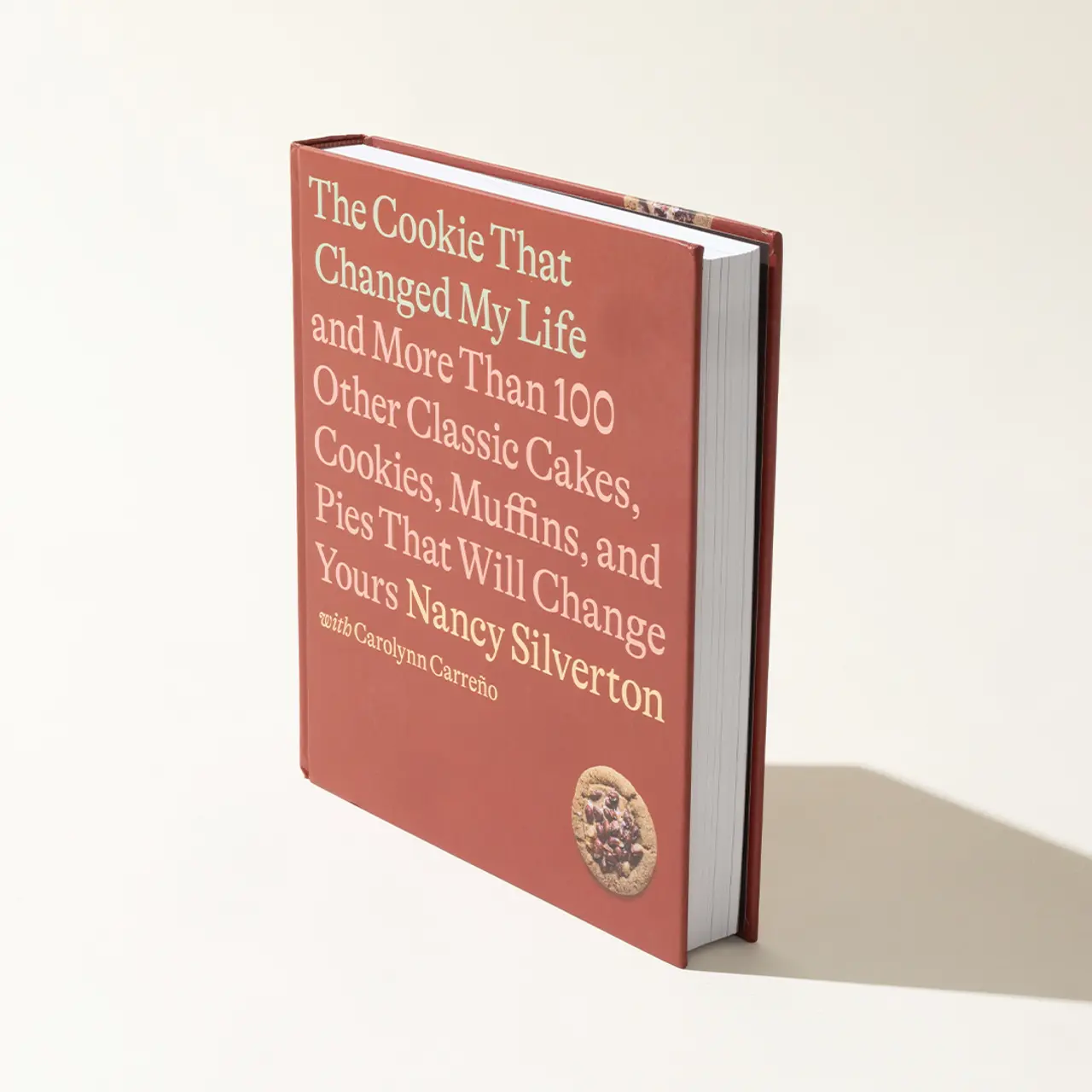 A red cookbook titled "The Cookie That Changed My Life" by Nancy Silverton is standing upright against a white background with a shadow to its right.